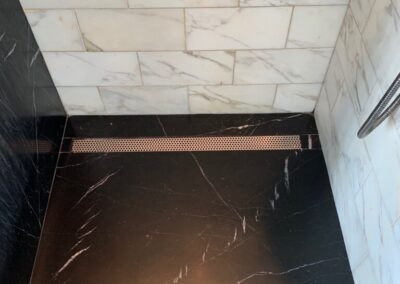 A black and white tiled shower stall with a light shadow