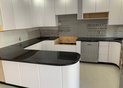 A kitchen with white cabinets and black counter tops