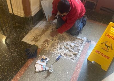 A man in a red shirt is working on a damaged floor