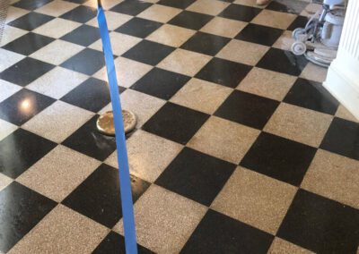 A black and white checkered floor with a blue tape with a person standing nearby with vacuum equipments